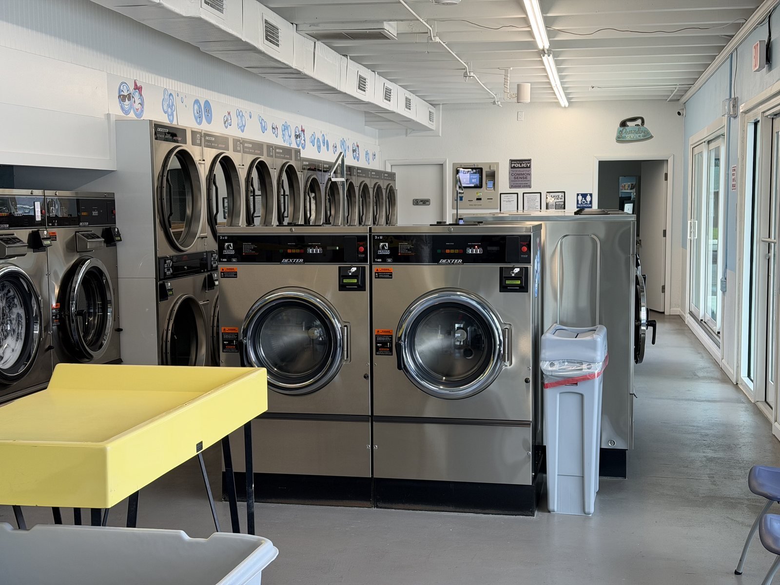 Original Ridgewood laundromat interior with Dexter machines, folding tables, carts and seating